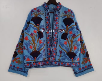 May include: A light blue embroidered jacket with a floral pattern in shades of red, purple, brown, and black. The jacket has a mandarin collar and a front closure. The text "SPIRITOFTHREAD" is embroidered on the front of the jacket.