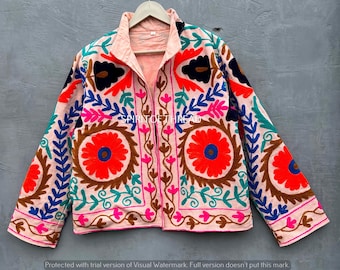 Op de afbeelding: Een roze geborduurde jas met bloemenpatronen in tinten rood, oranje, blauw, groen en roze. De jas heeft een kraag en lange mouwen.