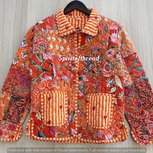 May include: A quilted jacket featuring a vibrant orange and red floral patchwork pattern with white striped trim on the collar, cuffs, and two front pockets. The text "Spiritofthread" is printed across the center of the garment.
