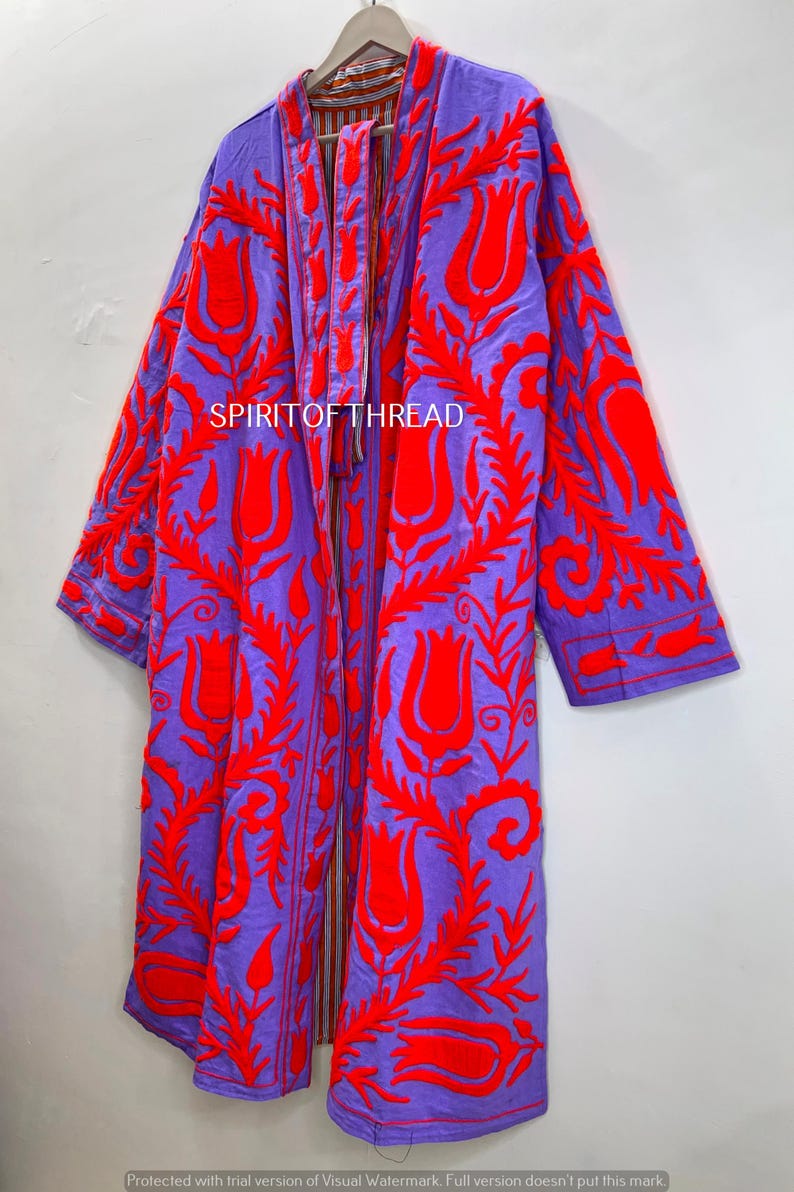 May include: A long, open-front coat in a vibrant purple hue, adorned with intricate red floral embroidery. The coat features a bold design with the text "SPIRITOFTHREAD" visible. This statement piece is a striking addition to any wardrobe.