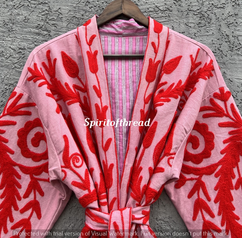 May include: A light pink robe with red floral embroidery. The robe has a striped pink and white lining and a matching belt. The text "Spiritofthread" is visible on the robe.
