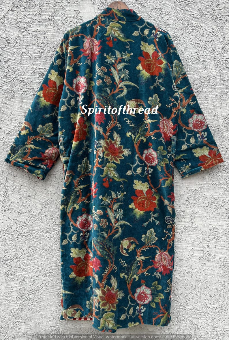 Pode incluir: Um roup&atilde;o com estampa floral azul-petr&oacute;leo com detalhes em vermelho e verde. O roup&atilde;o apresenta um design longo e fluido com uma estampa bot&acirc;nica. O texto "Spiritofthread" &eacute; vis&iacute;vel no roup&atilde;o. O roup&atilde;o &eacute; feito de um material macio e aveludado.