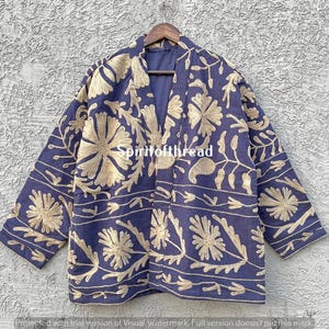 Pode incluir: Uma jaqueta azul marinho com um padrão de bordado floral dourado. A jaqueta tem manga comprida e uma abertura frontal estilo quimono.