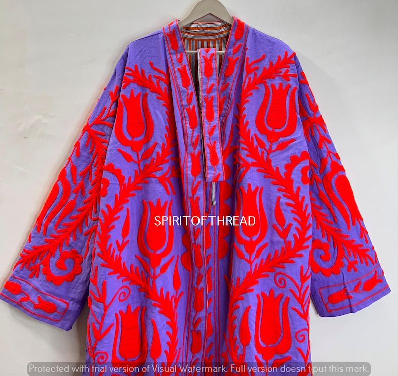 May include: A purple jacket with vibrant red floral embroidery. The jacket features a long, open design with a matching embroidered tie closure. The text "SPIRITOFTHREAD" is visible. The jacket is hanging on a wooden hanger.