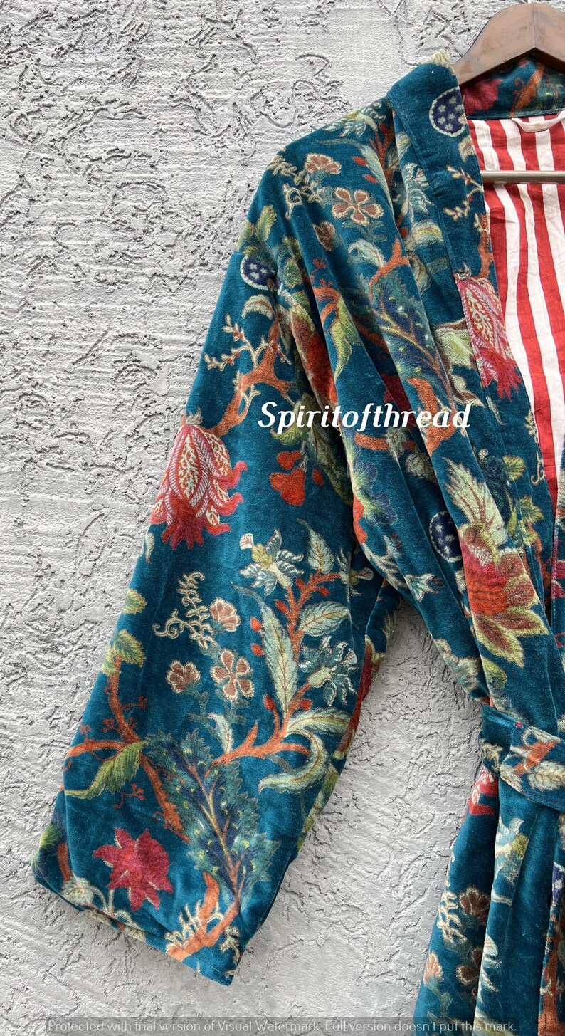 Pode incluir: Um roup&atilde;o de veludo azul-petr&oacute;leo com um padr&atilde;o floral em vermelho, laranja e verde. O forro interior do roup&atilde;o apresenta riscas vermelhas e brancas. O texto "Spiritofthread" &eacute; vis&iacute;vel.