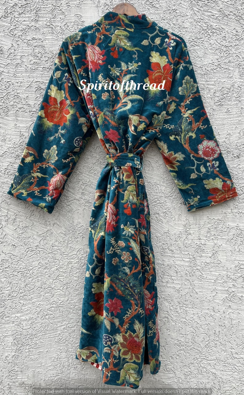 Pode incluir: Um roup&atilde;o azul-petr&oacute;leo com um padr&atilde;o floral em vermelho, laranja e verde. O roup&atilde;o tem mangas compridas e um cinto de amarrar. O texto "Spiritofthread" &eacute; vis&iacute;vel no roup&atilde;o. O roup&atilde;o &eacute; exibido contra uma parede branca texturizada.
