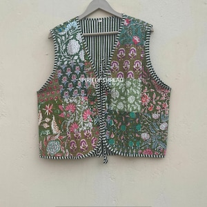 Puede incluir: Un chaleco acolchado con un diseño de patchwork con estampados florales en tonos verdes, rosas y blancos. El chaleco tiene un interior a rayas y un cierre de lazo. El texto "SPIRIT OF THREAD" es visible.