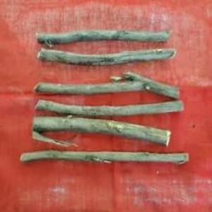 Peut inclure: Cinq bâtonnets en bois naturel disposés en rangée sur un fond de tissu rouge. Les bâtonnets ont tous à peu près la même longueur et la même épaisseur, et ils ont un aspect naturel et rustique.