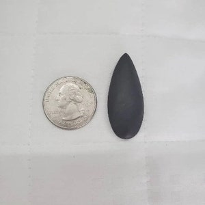 May include: A black, teardrop-shaped stone pendant. The pendant is about the size of a US quarter.
