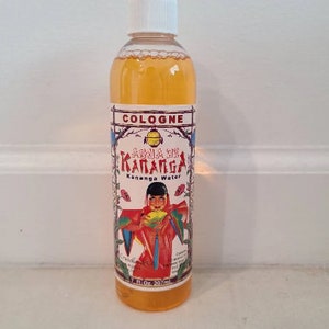 Op de afbeelding: Een doorzichtige glazen fles cologne met een witte dop. Het etiket is geel en rood met de tekst "COLOGNE", "AGUA DE KANANGA" en "Kananga Water". De fles is 7 fl oz (207 ml).
