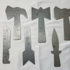 Peut inclure: Six silhouettes d'outils en métal, dont un marteau, une hache, un couteau et une flèche. Les silhouettes sont découpées dans du métal et ont une finition métallique lisse.