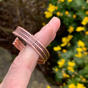 Op de afbeelding: Een koperen draad armband met een gevlochten ontwerp. De armband is gemaakt van meerdere koperen draden die samen zijn gevlochten om een unieke en stijlvolle look te cre&euml;ren.
