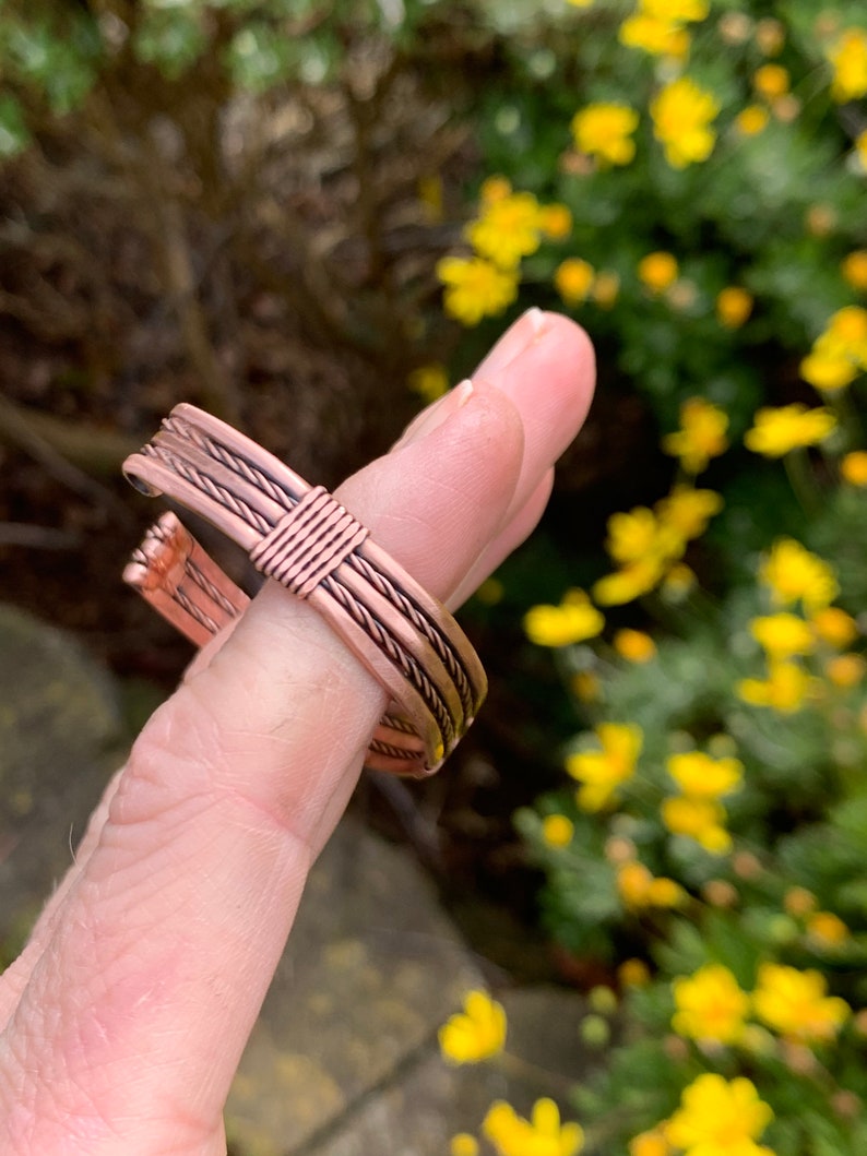 Op de afbeelding: Een koperen draad armband met een gevlochten ontwerp. De armband is gemaakt van meerdere koperen draden die samen zijn gevlochten om een unieke en stijlvolle look te cre&euml;ren.
