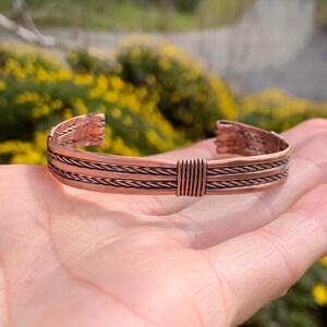 Op de afbeelding: Een koperen armband met een gevlochten ontwerp. De armband is gemaakt van drie gevlochten koperdraden.