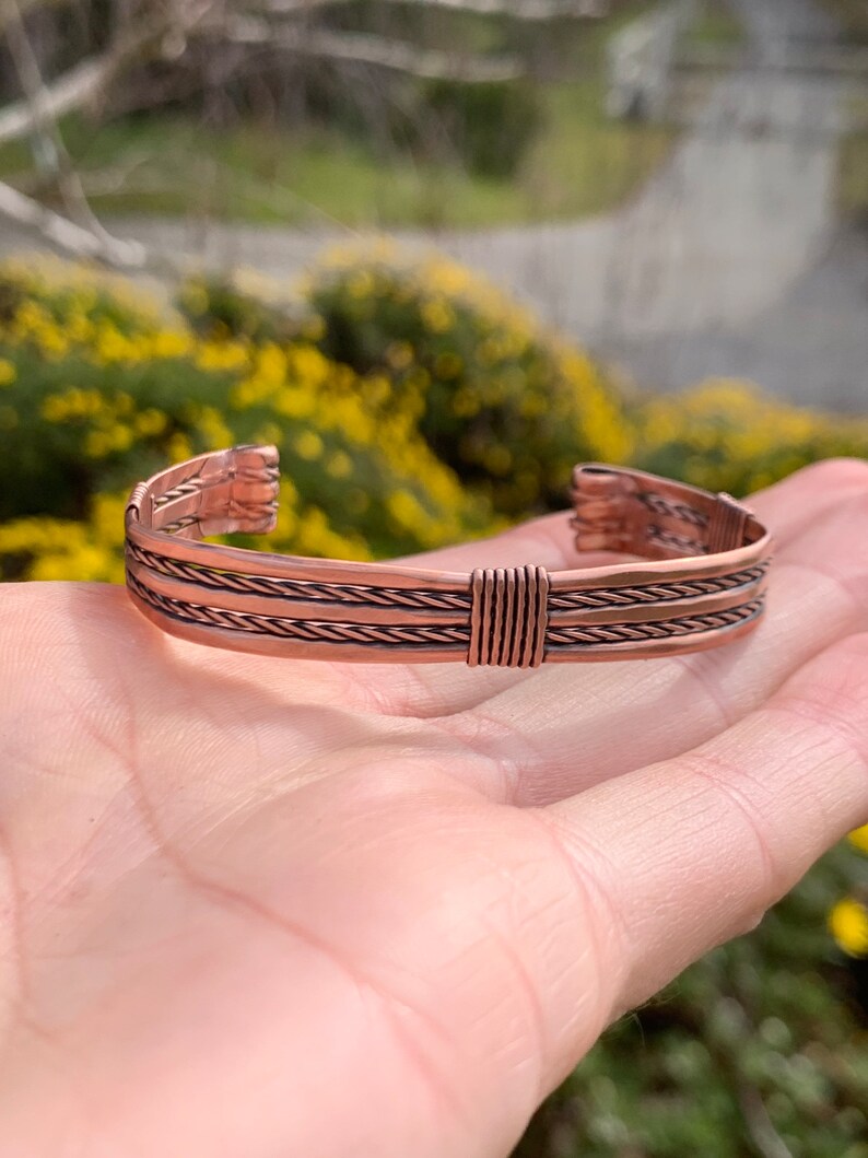 Op de afbeelding: Een koperen armband met een gevlochten ontwerp. De armband is gemaakt van drie gevlochten koperdraden.
