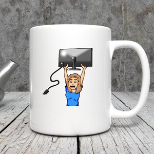K&ouml;nnte beinhalten: Wei&szlig;e Keramiktasse mit einer Cartoon-Illustration einer Person, die einen Computermonitor &uuml;ber ihrem Kopf h&auml;lt. Die Person tr&auml;gt ein blaues Oberteil und hat einen &uuml;berraschten Gesichtsausdruck. Ein schwarzes Netzkabel mit Stecker erstreckt sich vom Monitor.