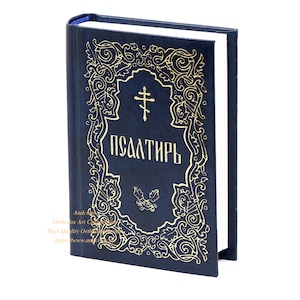 May include: A navy blue book with gold ornate detailing and the word "Псалтирь" in gold lettering. The cover features a cross and floral designs. The book's pages are white, and the spine is blue.