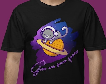 May include: Black t-shirt featuring a cartoon cat in a space helmet sitting on a planet with rings. The design includes a purple and blue galaxy background and the text "Give me some space" in a cursive font.