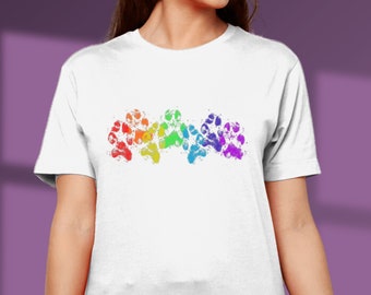 May include: White t-shirt featuring a rainbow paw print design. The paw prints are in the colours of the rainbow, red, orange, yellow, green, blue, indigo, and violet.