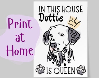 May include: A white and black Dalmatian dog with a crown above its head. The text "In this house Dottie is Queen" is printed below the dog. The text "Print at Home" is in a purple box in the upper left corner of the image.