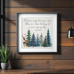 May include: Framed art print featuring a watercolor illustration of pine trees and a reindeer. The print includes the quote "Between every two pine trees there is a door leading to a new way of life" by John Muir.