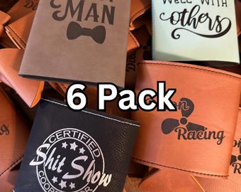 May include: A collection of drink koozies in various colors, including brown, black, and teal. Some koozies have text that reads "Best Man," "Drinks well with others," "Certified Shit Show Coordinator," and "Racing."