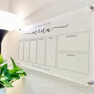Puede incluir: Un tablero de men&uacute; semanal de acr&iacute;lico blanco con texto negro. El tablero tiene siete columnas para cada d&iacute;a de la semana, con un espacio para escribir en cada columna. El texto en la parte superior dice "Esta semana en el men&uacute;". El texto en la parte inferior dice "The Loffett Family".