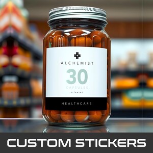 May include: A clear glass jar with a silver lid filled with orange capsules. The jar has a white label with the word "ALCHEMIST", the number "30", and the word "CAPSULES" and "VITAMINS". The bottom of the label reads "HEALTHCARE".