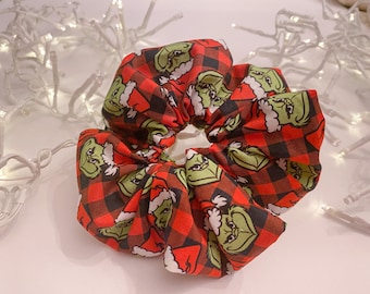 Puede incluir: Scrunchie de cuadros rojos y negros con un patrón verde del Grinch.