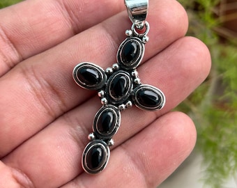 Op de afbeelding: Een zilveren kruis hanger met zwarte onyx stenen. Het kruis is gemaakt van sterling zilver en heeft een gepolijste afwerking. De onyx stenen zijn gezet in een bezel setting en zijn omgeven door kleine zilveren kralen.