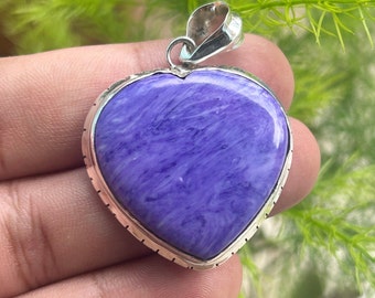 May include: A silver heart-shaped pendant with a purple and white stone. The stone has a swirling pattern.