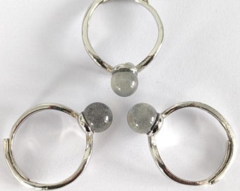 May include: Three silver rings with a gray stone bead on each ring.