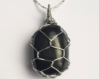 May include: A black gemstone pendant necklace with a silver chain. The gemstone is encased in a silver wire cage.