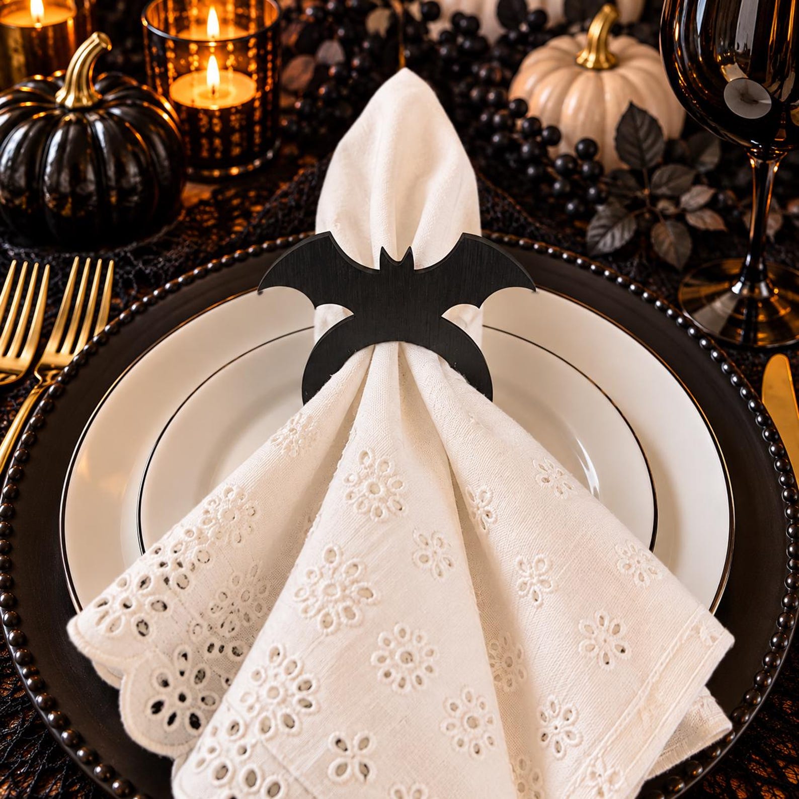 A Bat Clip Across a White Fan White cloth napkin gathered through a black bat-shaped ring on an ivory plate.