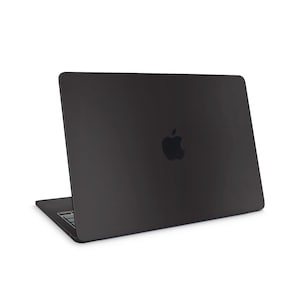 Puede incluir: Un ordenador portátil negro con el logotipo de Apple en la tapa. El portátil está abierto, mostrando el teclado y la pantalla. El dispositivo está sobre un fondo blanco.