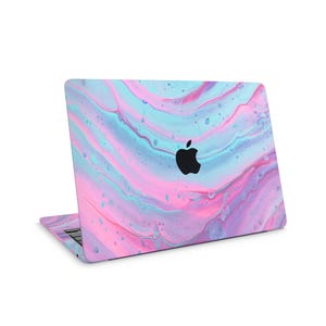 Puede incluir: Un ordenador portátil con un diseño abstracto y colorido. La cubierta presenta un patrón arremolinado de tonos rosas, azules y morados, con un logotipo de Apple negro. El portátil está abierto, mostrando el teclado y la pantalla.