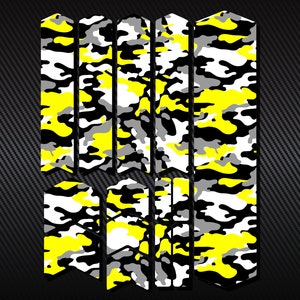 May include: A collection of camouflage stickers in yellow, black, grey, and white. The stickers are arranged vertically, with a mix of rectangular and angled shapes. The background has a dark grey carbon fibre texture.