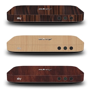 May include: Three Sky Q boxes with different wood grain finishes. The boxes are black with a silver "Sky" logo and have a wood grain finish in dark brown, light brown, and reddish brown.