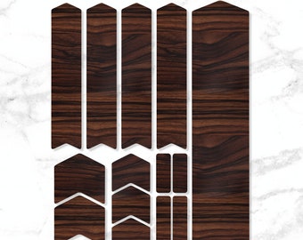 May include: A set of brown wood-grain bike frame protection stickers. The set includes long strips, small arrows, and rectangular shapes.