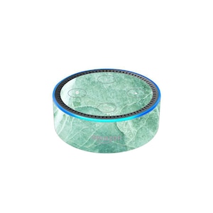 Może przedstawiać: Skórka w zielonym wzorze marmuru do inteligentnego głośnika Amazon Echo Dot. Skórka ma jasnoniebieski akcent wokół krawędzi.