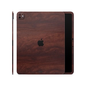 Puede incluir: Una funda para iPad de madera marrón con un logotipo de Apple negro. La funda tiene un color marrón oscuro y un patrón de madera.