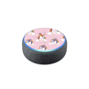 Puede incluir: Una piel con estampado rosa y blanco para un altavoz inteligente Amazon Echo Dot. El patrón presenta unicornios con arcoíris y nubes.