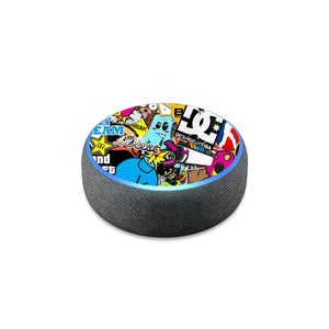 May include: A black Amazon Echo Dot smart speaker with a colorful sticker design featuring a variety of logos, graphics, and text, including "DC SHOE CO. USA" and "TEAM".