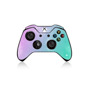 Op de afbeelding: Een zwarte Xbox-controller met een galaxy-thema ontwerp met een verloop van paarse, roze en blauwe kleuren. De controller heeft een wit Xbox-logo en zwarte knoppen.