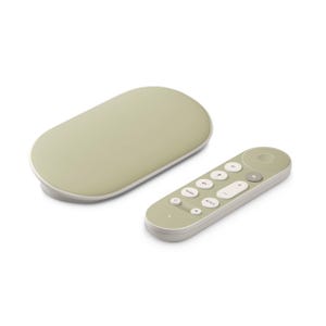 Op de afbeelding: Een saliegroene streaming-apparaat en afstandsbediening. Het ovale apparaat heeft een witte basis en de afstandsbediening heeft verschillende knoppen met witte en grijze accenten. De set is ontworpen voor home entertainment.