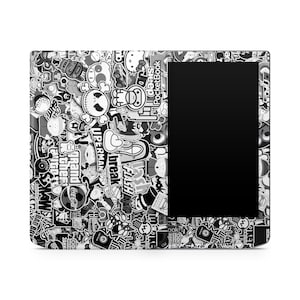 May include: An e-reader case covered in black and white stickers. The stickers feature various designs and text, including a skull, a soccer ball, and the words "Superman" and "Flash". The e-reader screen is black.