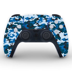 Może przedstawiać: Bezprzewodowy kontroler PlayStation 5 DualSense z wzorem kamuflażu w kolorze niebieskim i czarnym.