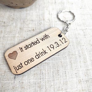 May include: Wooden keychain with a heart and the text "It started with just one drink 19.3.12"