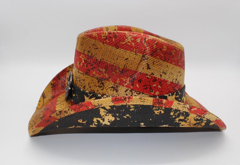 May include: A straw cowboy hat with a distressed red and yellow striped pattern. The hat features a black band and a silver-colored decorative element. The brim has a distressed black pattern.