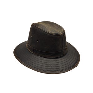 May include: A dark brown leather hat with a wide brim and a band around the crown. The hat has a distressed, weathered appearance, suggesting it's been worn. The hat's design is reminiscent of a safari or outdoor style.